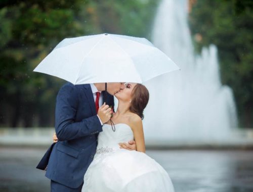 Couple de mariés qui s'embrasse sous un parapluie blanc