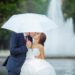 Couple de mariés qui s'embrasse sous un parapluie blanc